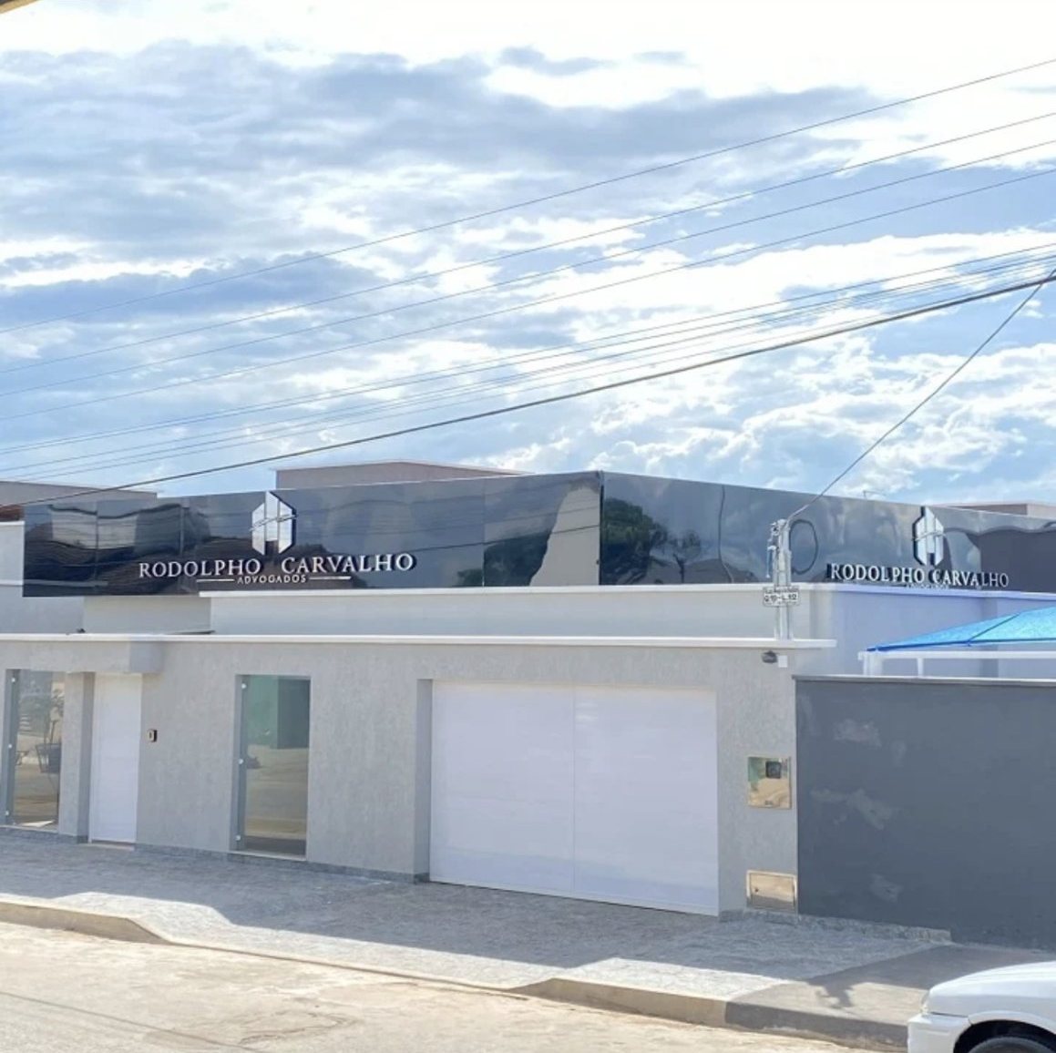 Fachada do escritório, com o letreiro Rodolpho Carvalho Advogados em painel preto espelhado